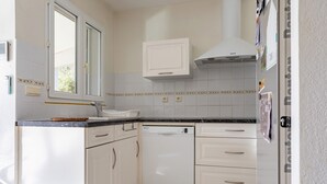A kitchen with white cabinets, a dishwasher, and a window. - La Massane - Three Bedroom House, Sleeps 6 (Argeles-sur-Mer)
