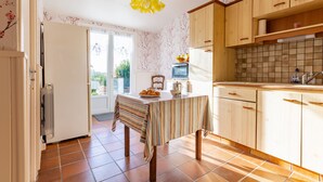 A kitchen with wooden cabinets, a tiled backsplash, and a striped tablecloth. - L'Orchidée - Two Bedroom House, Sleeps 6 (Limerzel)