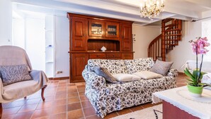 A living room with a sofa, armchair, wooden cabinet, and staircase. - L'Orchidée - Two Bedroom House, Sleeps 6 (Limerzel)