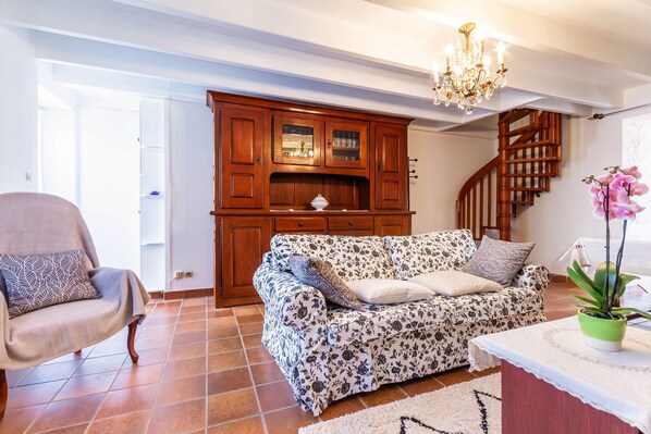 Un salon avec un canapé, un fauteuil, un meuble en bois et un escalier.