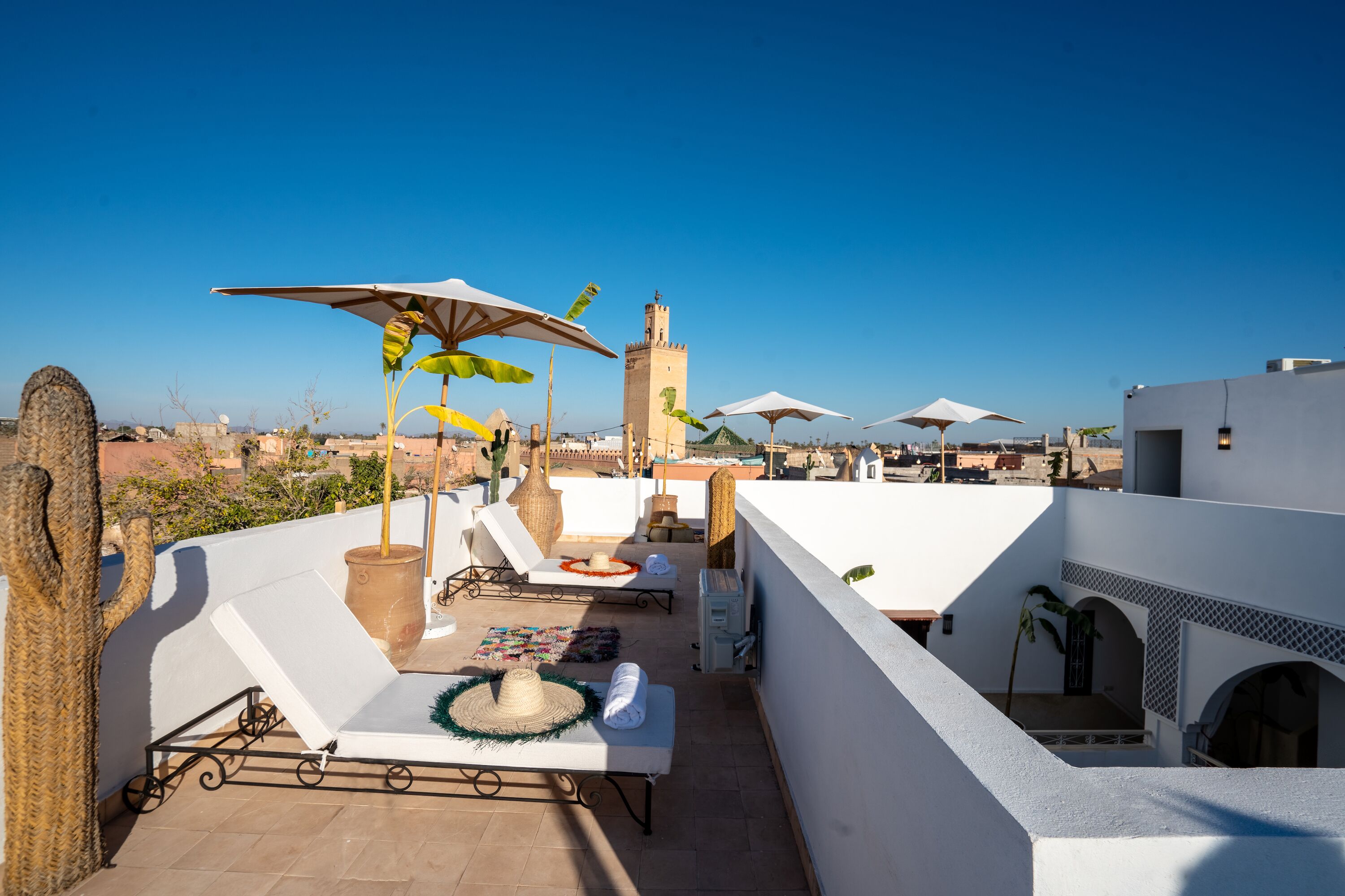 Terraza en la azotea con sillones de descanso, sombrillas y vistas a una torre.