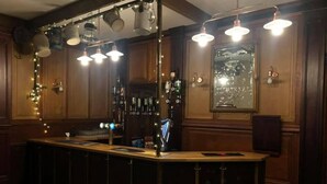 Una zona de bar con una barra larga, varias lámparas y una variedad de botellas y vasos en estanterías.