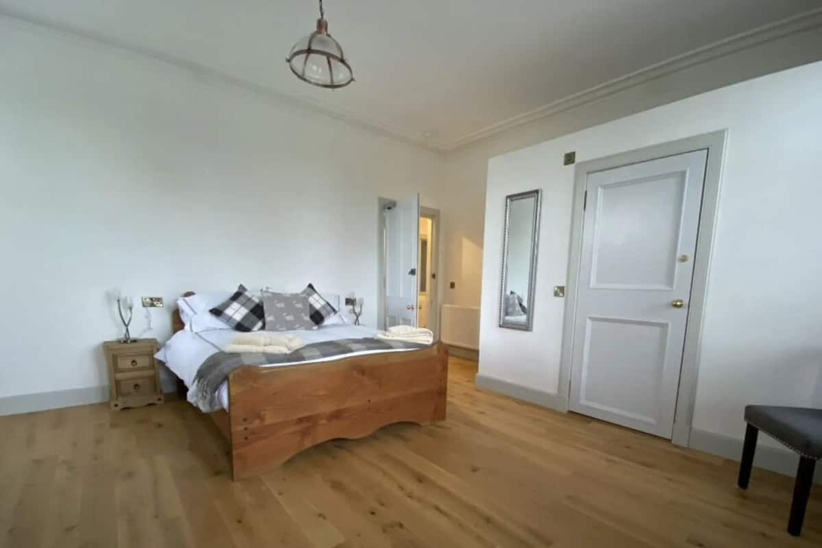 A bedroom with a wooden bed, a nightstand, a chair, and a door.