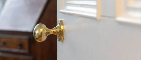 A door with a brass handle and a room number plate.