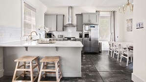 Een moderne keuken met een groot kookeiland, roestvrijstalen apparatuur en witte kasten.
