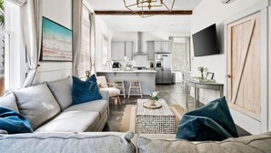 Een moderne woonkamer met een bank, salontafel en een keuken op de achtergrond.