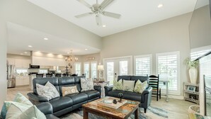 A spacious living room with a fireplace, a dining area, and a kitchen in the background. - Spacious Beachside Home w/ Long Gulf View, Covered Deck & Huge Primary Suite (Galveston)