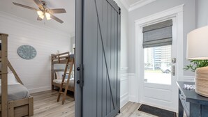 Une pièce avec un lit, une échelle, une porte et une horloge au mur.