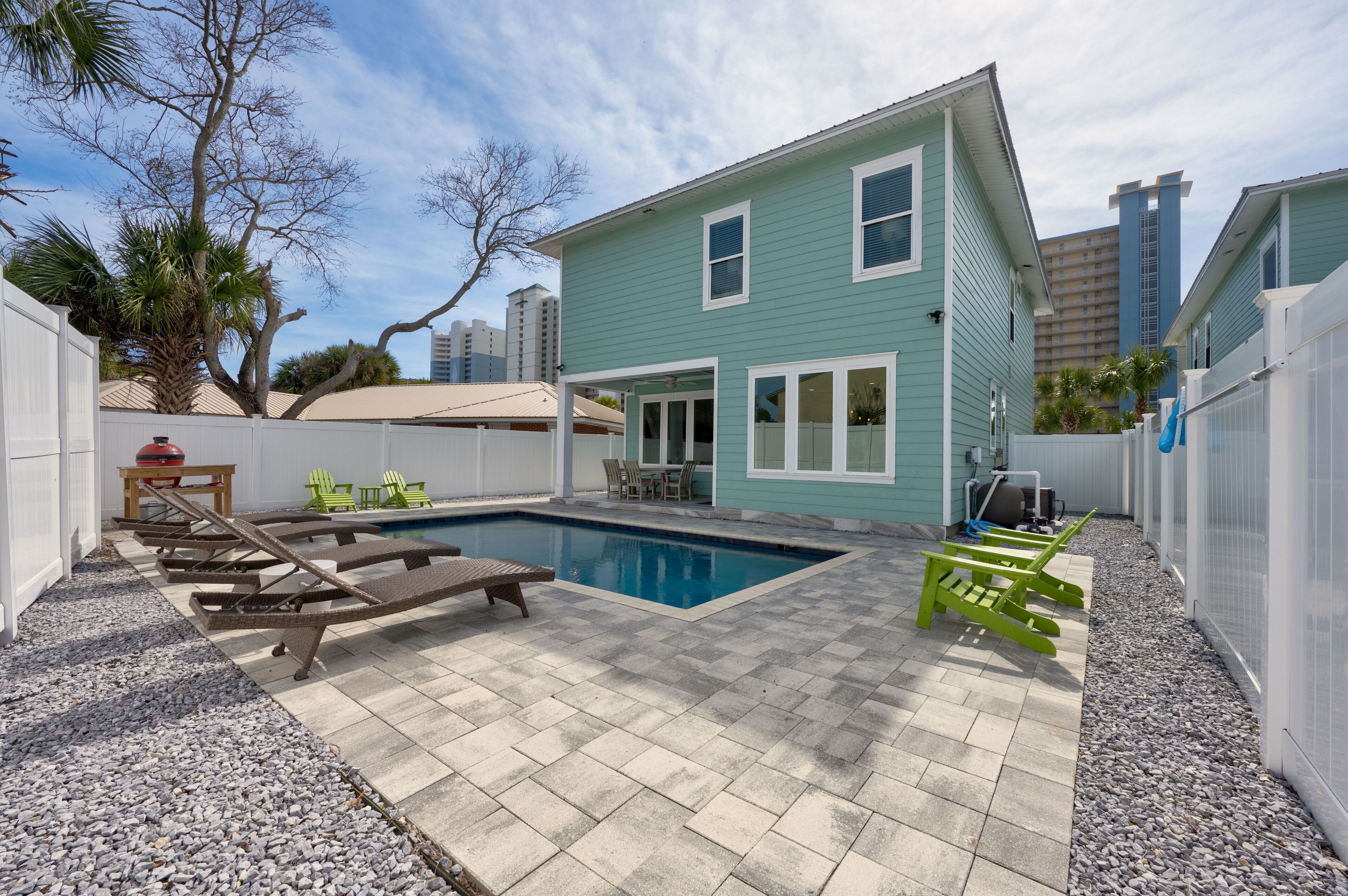 Un jardin avec une piscine, des chaises longues et un espace patio.