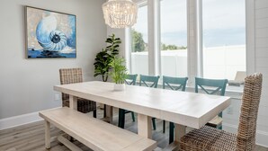 Un coin repas avec une table blanche, des chaises de couleur turquoise et un lustre suspendu.