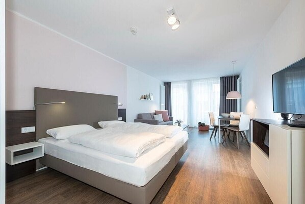 A modern hotel room with a large bed, a desk, and a TV. - Schönes Apartment mit Sonniger Terrasse, Sauna im Haus - nur 300 m zum Strand! (Nordseeheilbad Langeoog)