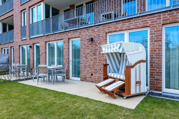 A modern apartment building with a brick facade, large windows, and a balcony with metal railings. - Ruhiges Top-apartment mit Terrasse und Sauna im Haus - nur 300 m zum Inselstrand (Nordseeheilbad Langeoog)