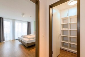 A hotel room with a bed, a wardrobe, and a bathroom with a shower. - Ruhiges Top-apartment mit Terrasse und Sauna im Haus - nur 300 m zum Inselstrand (Nordseeheilbad Langeoog)