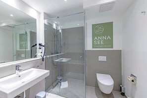 A modern bathroom with a glass-enclosed shower, a sink, and a toilet.