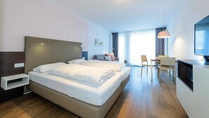 A modern hotel room with a large bed, a desk, a chair, and a television.