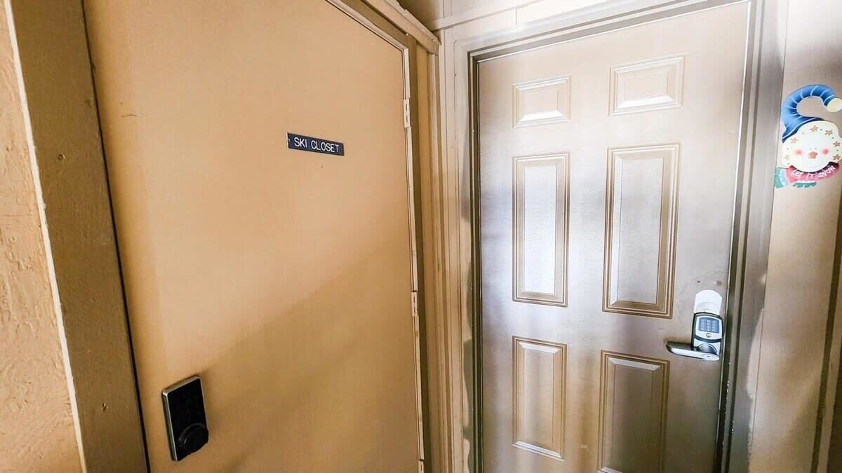 Habitación de hotel con puerta cerrada, letrero que indica guardarropa para esquíes y cerradura electrónica.