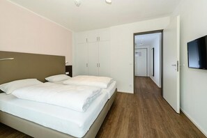 Una habitación de hotel moderna con cama, armario y televisor en la pared.