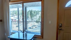 Ein Zimmer mit großem Fenster und Balkon mit Blick auf Bäume und einen Parkplatz.