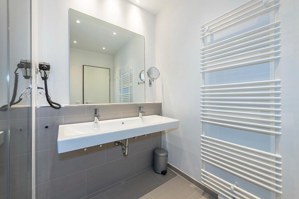 Een moderne badkamer met een wit wastafelmeubel, spiegel en handdoekhouder.