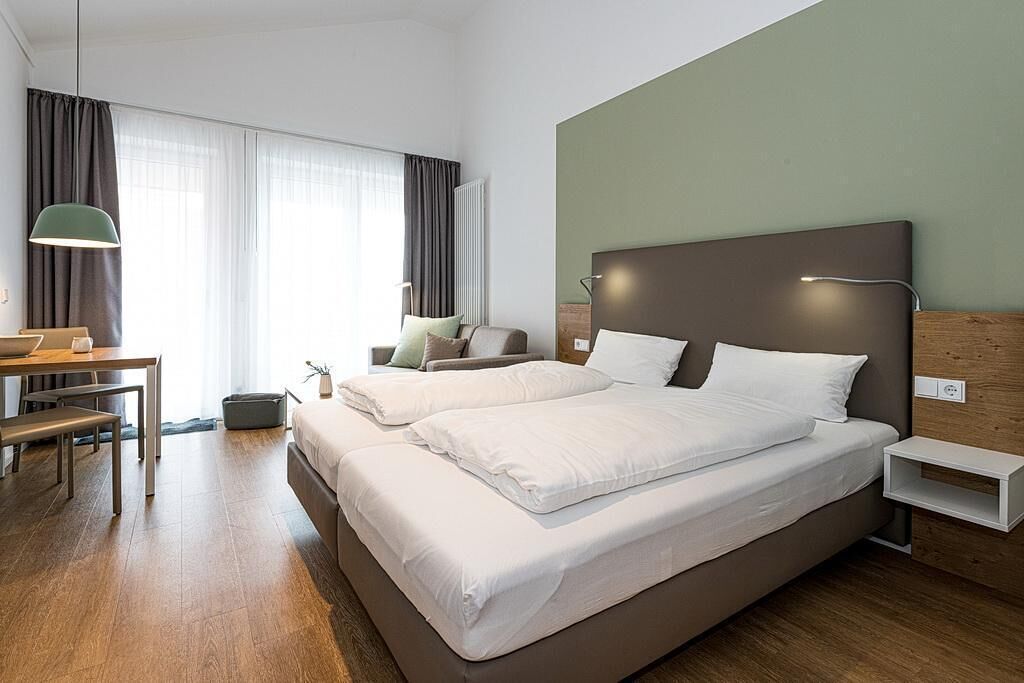Ein modernes Hotelzimmer mit einem großen Bett, einem Schreibtisch und einem Stuhl.