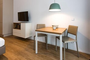 Et moderne værelse med et træspisebord, to stole, et fjernsyn på væggen og en pendel over bordet.