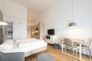Una habitación de hotel moderna con cama, escritorio, televisión y zona de comedor.