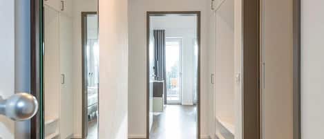 Ein Flur mit Blick in einen Raum, der ein Bett und ein Fenster zeigt.