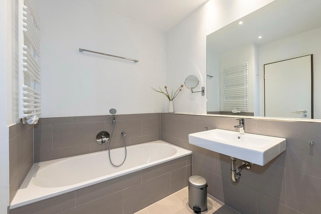 Ein modernes Badezimmer mit Badewanne, Waschbecken und Spiegel.