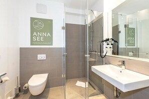 A modern bathroom with a glass shower enclosure, a white sink, and a toilet.