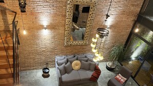 A modern living room with a brick wall, a grey sofa, a coffee table, and a mirror. - Luxury Stays (Tlacopac, Álvaro Obregón)