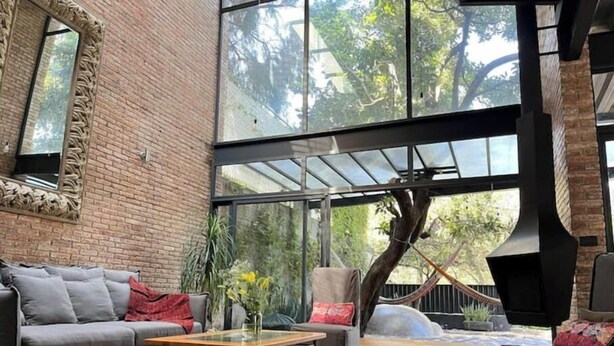 A modern living room with a brick wall, large windows, and a fireplace. - Luxury Stays (Tlacopac, Álvaro Obregón)