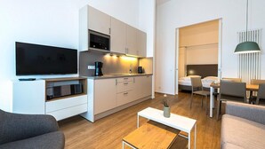 A modern, compact living space with a kitchenette, a flat-screen TV, a dining area, and a seating area.