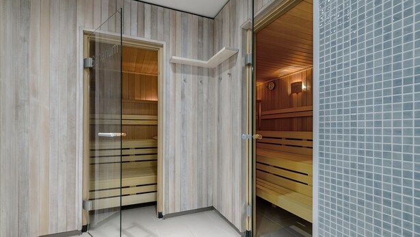 A modern bathroom with wooden paneling, a glass shower enclosure, and a tiled wall.