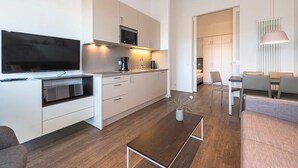 A modern kitchen with built-in appliances, a dining area with a table and chairs, and a living room with a sofa and a coffee table.