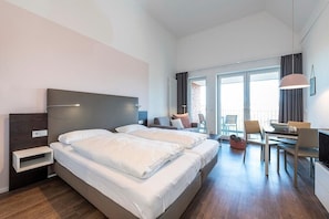Habitación de hotel con dos camas, un escritorio, una silla y una mesa de comedor.