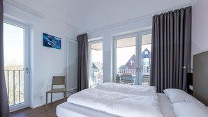 A hotel room with a large bed, a chair, a window, and a view of buildings outside.