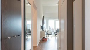 A modern hallway with a wooden door, a mirror, and a seating area with chairs and a small table.