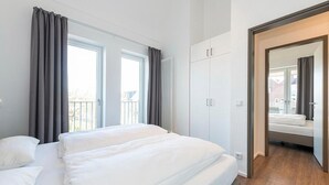 A modern bedroom with a large bed, a wardrobe, and a view of the outside.