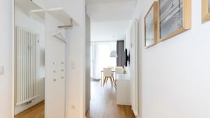 Un couloir moderne et bien éclairé, avec un radiateur blanc, un porte-manteau et un coin repas comprenant une table et des chaises.