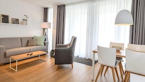 Un salon moderne comprenant un canapé, une table basse, un coin repas avec des chaises et une table, ainsi qu’une lampe.
