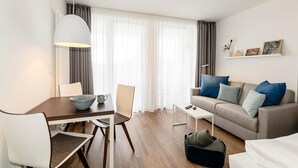 Una sala de estar moderna con una mesa de comedor, sofá y un ventanal con cortinas translúcidas.