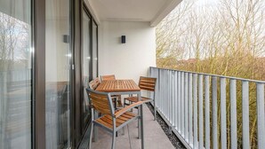 Ein Balkon mit Tisch und Stühlen, einem Metallgeländer und Blick auf Bäume.