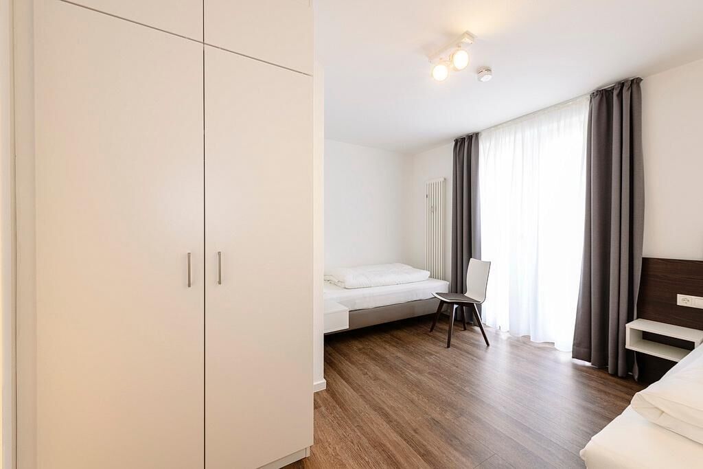 A modern bedroom with a bed, a chair, and a wardrobe.