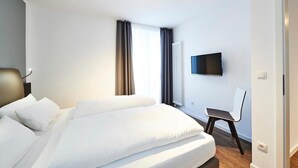 Ein modernes Hotelzimmer mit einem großen Bett, einem flachbildfernseher an der Wand und einem Sessel.