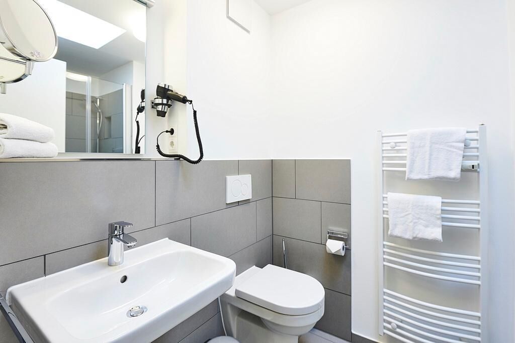 Een moderne badkamer met een wit wastafel, toilet en handdoekrek.