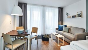 Uma sala de estar moderna com área de jantar, um sofá, uma mesa de centro e um abajur.