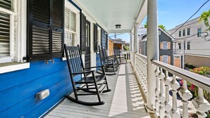 A porch with rocking chairs, a white railing, and a blue exterior wall. - Downtown Duplex - St Philip St (Charleston)