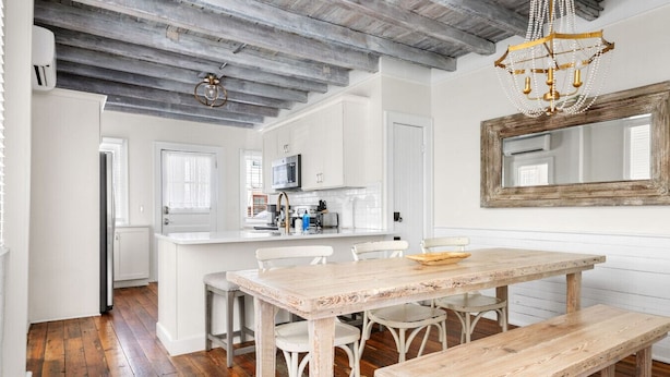 A kitchen with white cabinets, a wooden dining table, and a chandelier. - Downtown Duplex - St Philip St (Charleston)