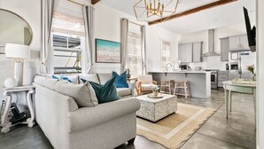 A modern living room with a sofa, coffee table, and a view of the kitchen. - Downtown Duplex - St Philip St (Charleston)