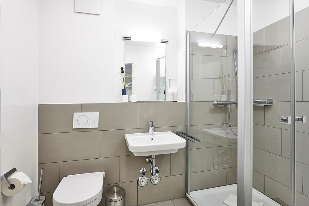 A modern bathroom with a toilet, sink, and glass-enclosed shower.